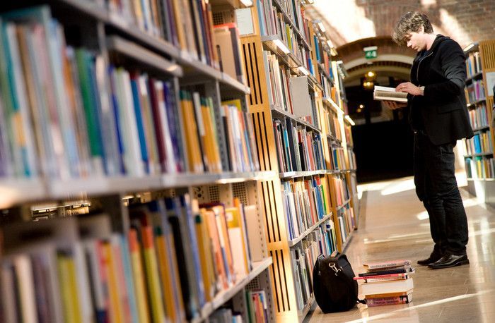 Kille som läser i en bok på ett bibliotek