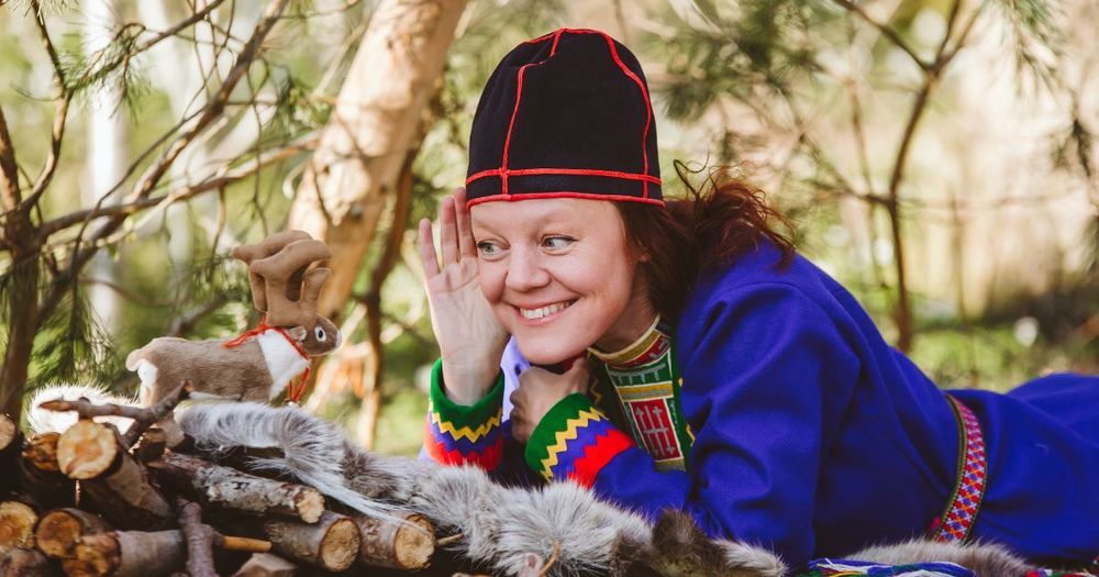 En liten ren och kvinna i samisk dräkt