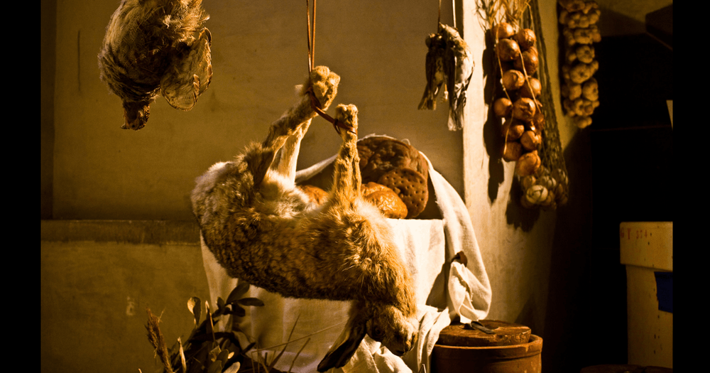 En hare, en ripa samt knippen med lök upphängda i ett medeltida kök