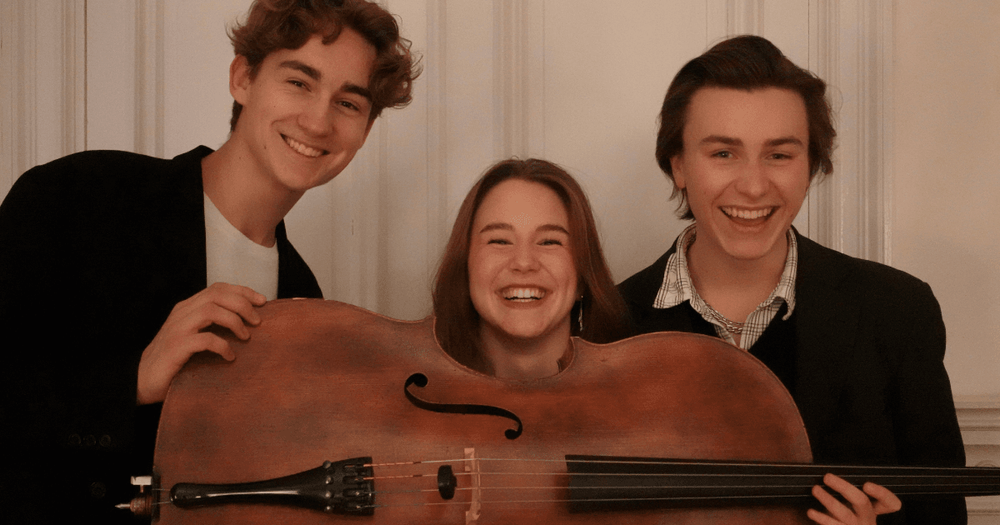 Tre musiker är glada och håller i en cello