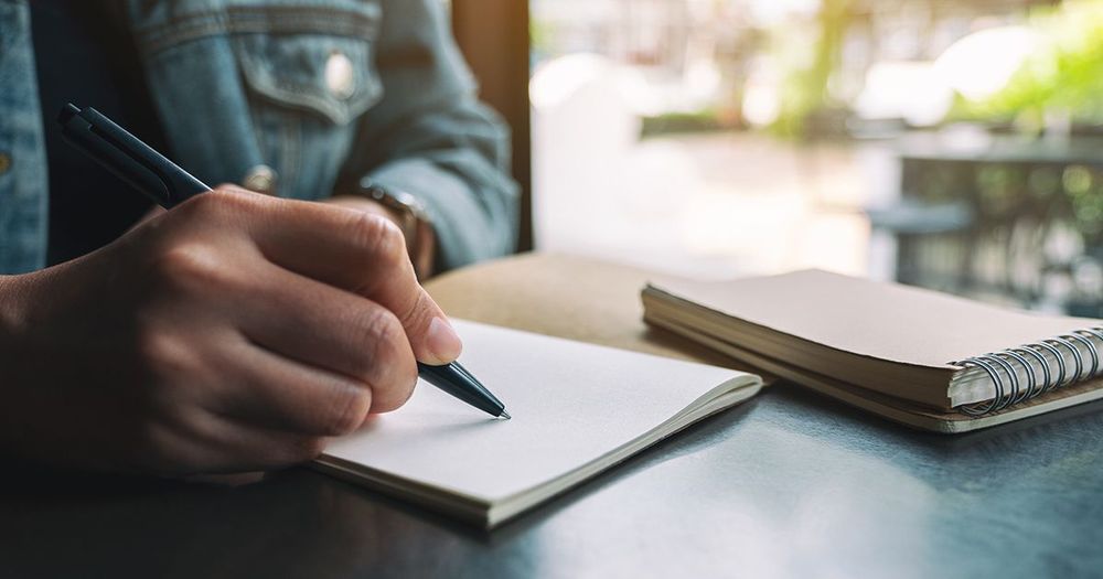 Hand som skriver med bläckpenna i en anteckningsbok.