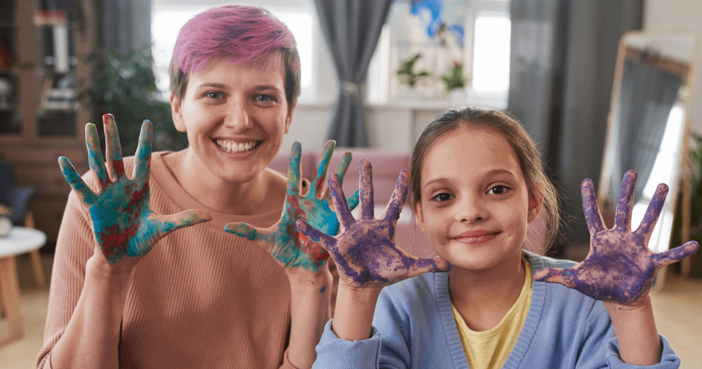 En kvinna och ett barn med målade händer i luften