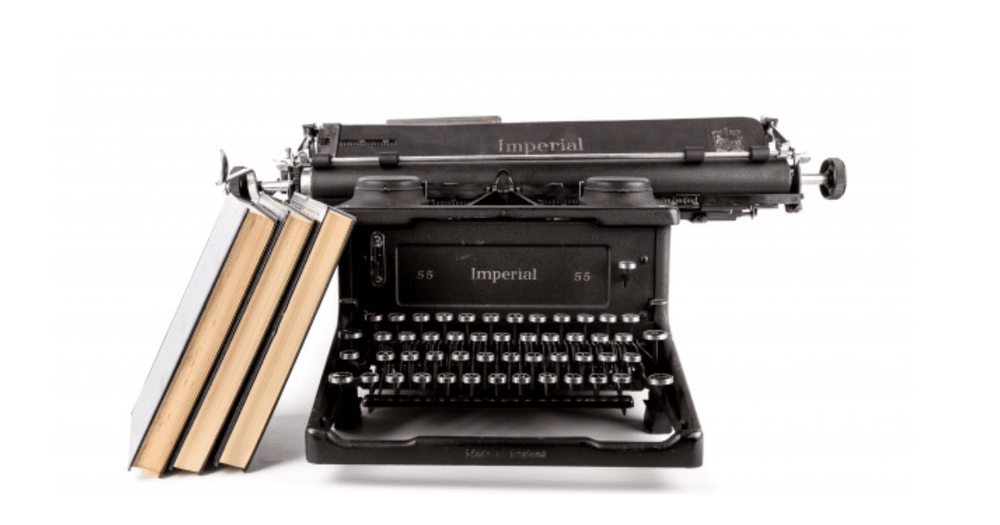 Tre böcker står lutade mot en gammeldags svart skrivmaskin.