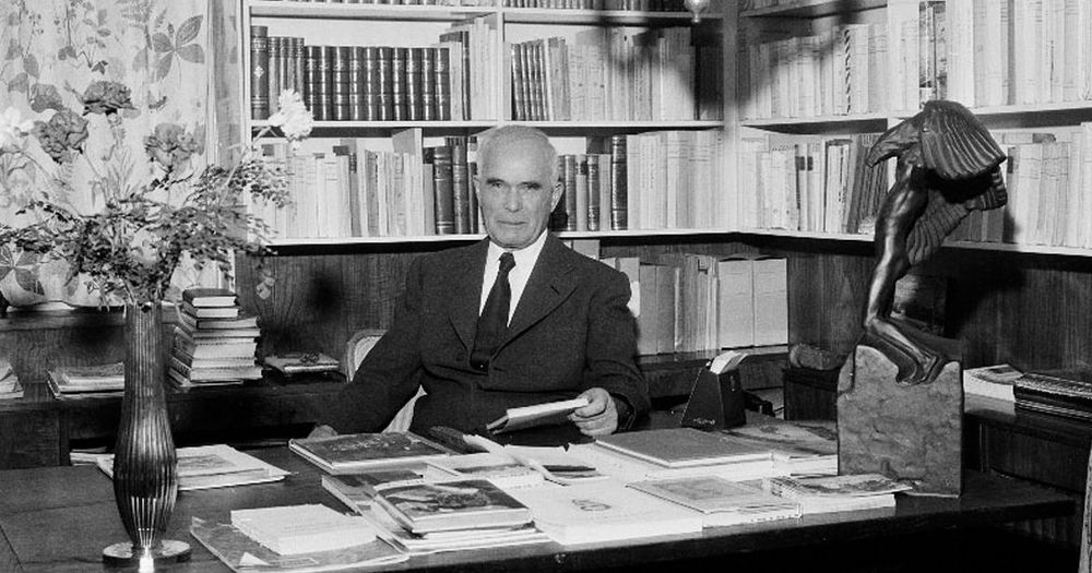 Svartvitt porträtt på en man bakom sitt arbetsbord.