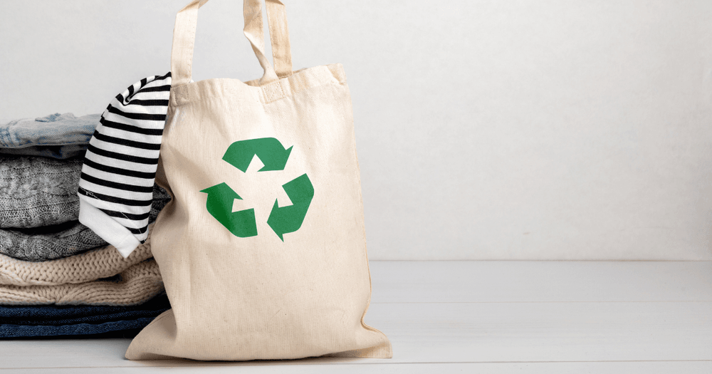 En hög med kläder och en tygkasse med cirkulartionssymbolen på